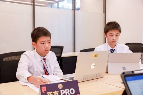 2 children at a desk preparing a debate