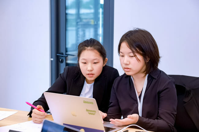 two girls inspect paper